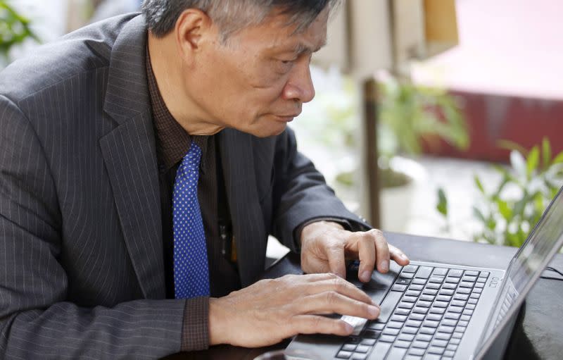 FILE PHOTO: Nguyen Quang A writes a comment on Facebook while sitting at a cafe after an interview in Hanoi