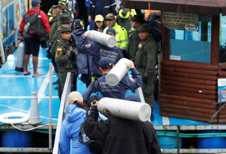 Firefighters carry oxygen tanks as the search for people believed to be missing after a tourist boat sank on Sunday continues, in Guatape, Colombia June 26, 2017. REUTERS/Fredy Builes