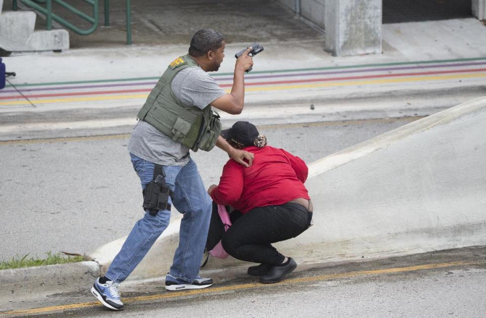 A law enforcement officer evacuates a civilian from an area at Fort Lauderdale–Hollywood International Airport, Friday, Jan. 6, 2017, in Fort Lauderdale, Fla. A gunman opened fire in the baggage claim area at the airport Friday, killing several people and wounding others before being taken into custody in an attack that sent panicked passengers running out of the terminal and onto the tarmac, authorities said. (AP Photo/Wilfredo Lee)