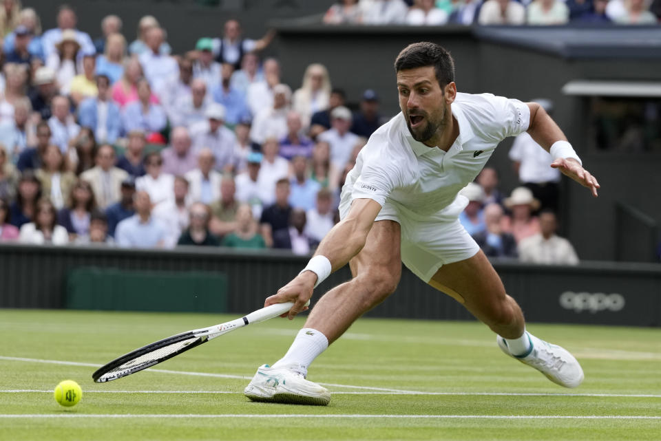 Serbia's Novak Djokovic stretches to return to Spain's Carlos Alcaraz in the final of the men's singles on day fourteen of the Wimbledon tennis championships in London, Sunday, July 16, 2023. (AP Photo/Kirsty Wigglesworth)