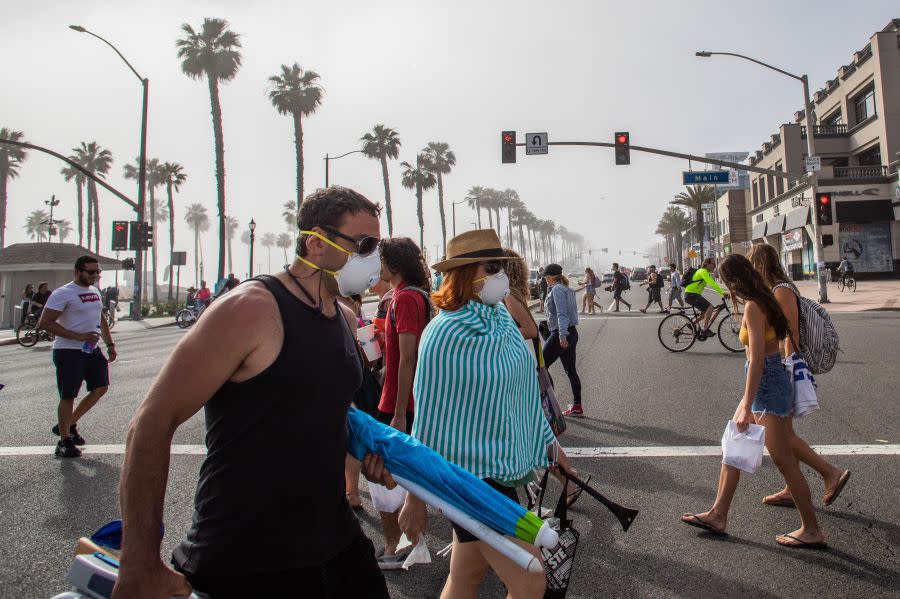 People cross the street, some wearing masks, amid the novel coronavirus pandemic in Huntington Beach on April 25, 2020. (APU GOMES/AFP via Getty Images)