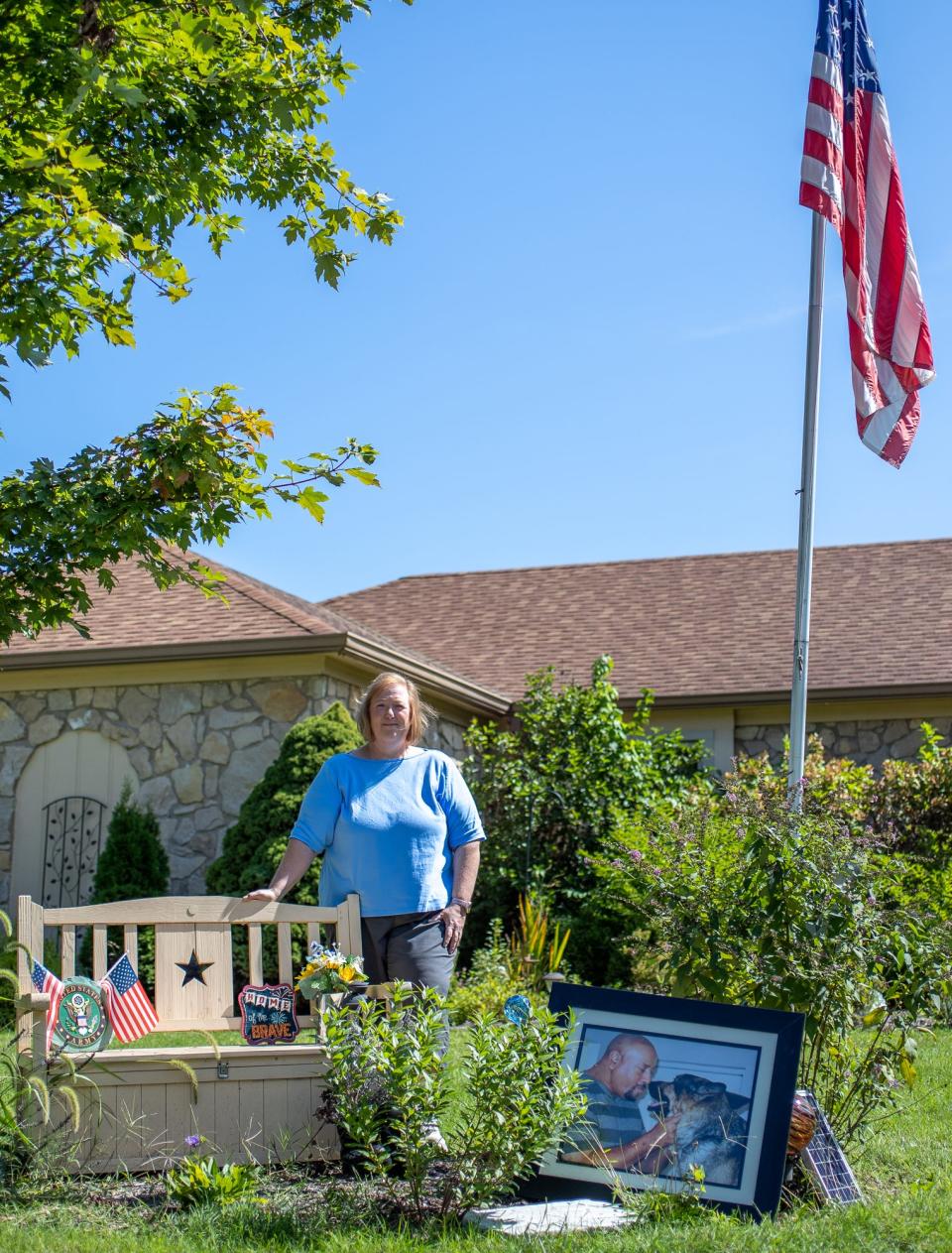 Jennifer Wright stands near a bench in her front yard Friday, Sept. 3, 2021, and a picture of her late husband Wayne and his police K9 Bear. Wayne, who died in 2018 after going into cardiac arrest, was cremated and his ashes are housed inside the bench, under an American flag. He was a Vietnam veteran and former Marion County sheriff's deputy.