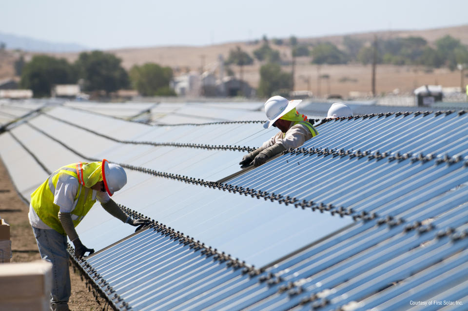 Two workers working on a First Solar power plant that's under construction.