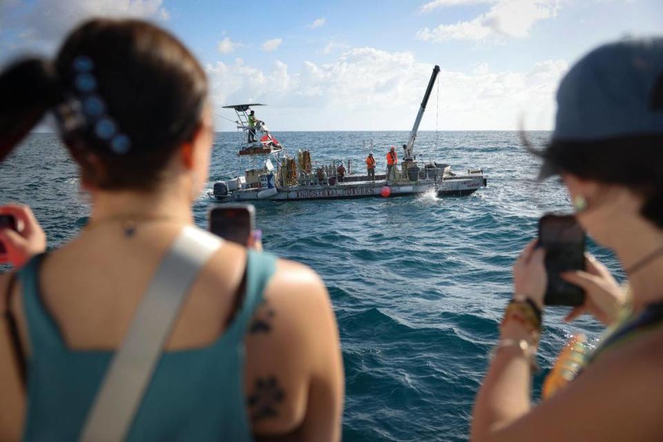 Jeffrey Pace’s daughters, Mackenzie, left, and Lexi, watch as his reef ball gets stuck as it is lowered into the ocean at the Golden Beach Reef Site near Haulover Beach. “He’s always been stubborn,” said Mackenzie as she watched.