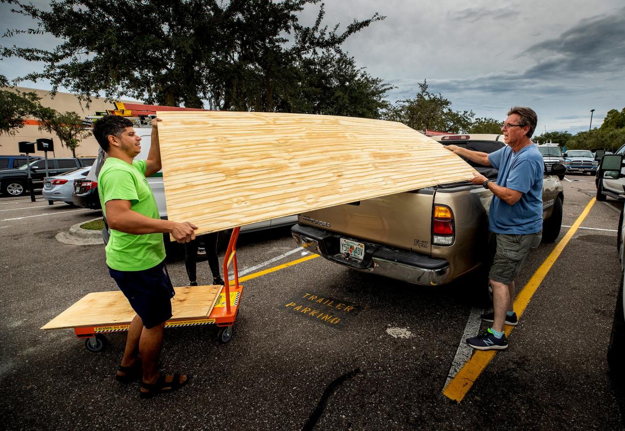 Raphael Berrios gets help loading construction materials from Ray Bryant, right, at Home Depot in preparation for Hurricane Ian in Lakeland on Tuesday. His wife, Leslie Rodriguez, said they have plenty of experience getting prepared as they had lived through hurricanes in Puerto Rico.