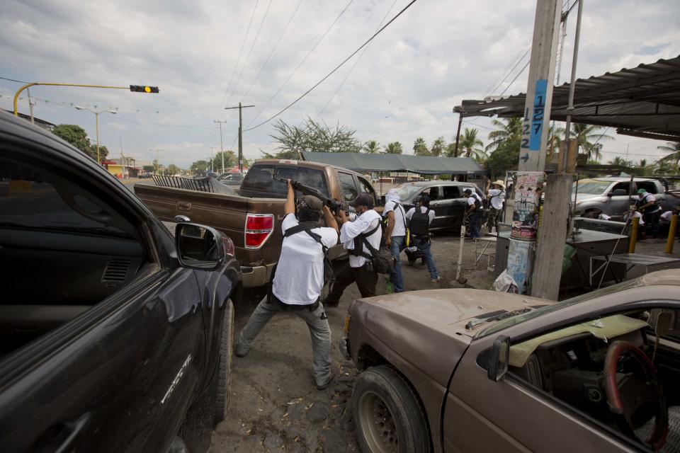 Men belonging to the Self-Defense Council of Michacan, (CAM), engage in a firefight while trying to flush out alleged members of the Knights Templar drug cartel from the town of Nueva Italia, Mexico, Sunday Jan. 12, 2014. The vigilantes say they are liberating territory in the so-called Tierra Caliente and are aiming for the farming hub of Apatzingan, said to be the cartel's central command. Mexican military troops are staying outside the town and there are no federal police in sight. (AP Photo/Eduardo Verdugo)