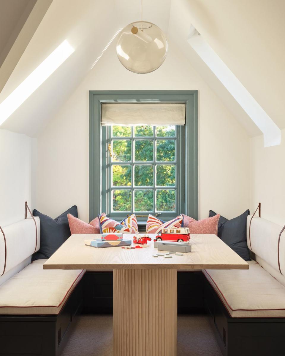 a room with a table and a window with a light above it