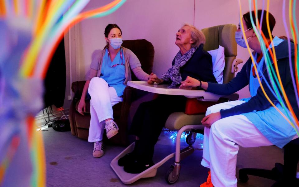 Medical workers wearing protective face masks accompany a resident during a relaxation session at the "la maison du moulin" retirement home  - REUTERS/Pascal Rossignol