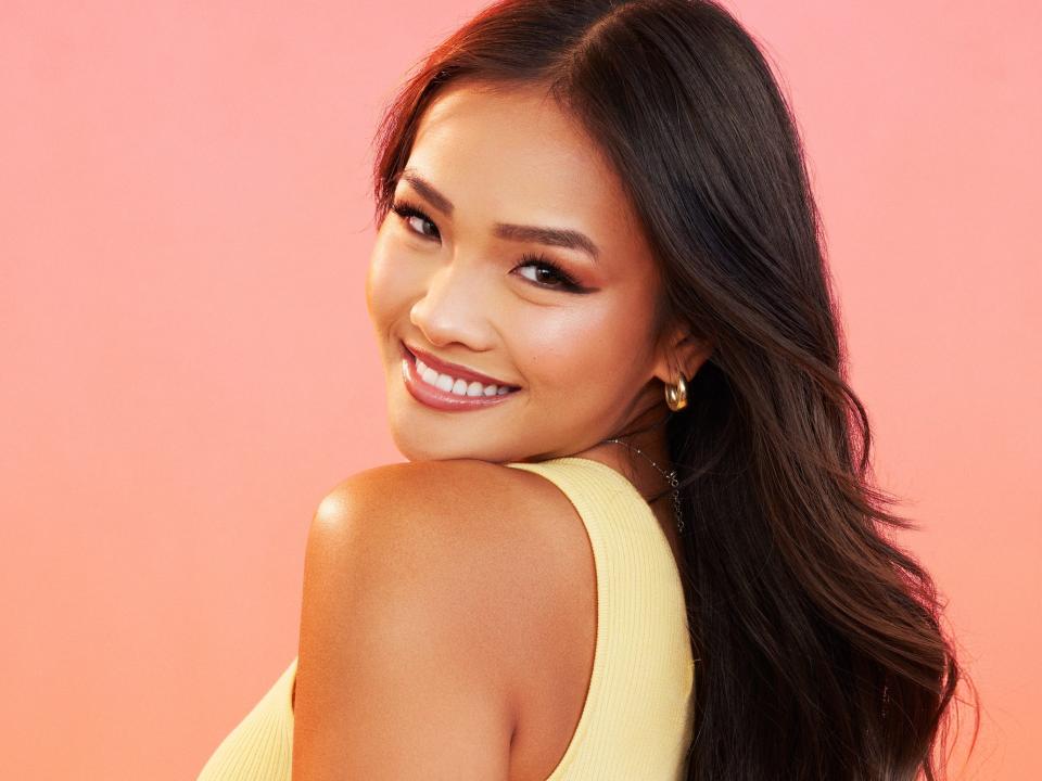 Jenn poses for photos in a yellow dress, gold earrings, and silver bracelet.