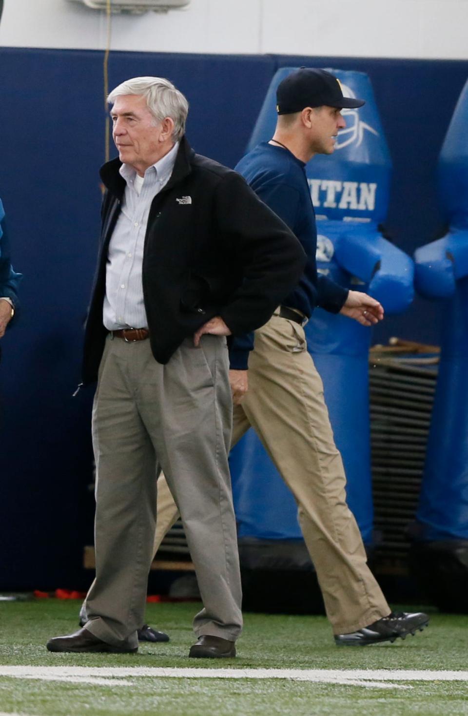 Former Michigan head coach Gary Moeller watches from the sidelines as new head coach Jim Harbaugh walks by during Michigan football practice March 19, 2014, in Ann Arbor.