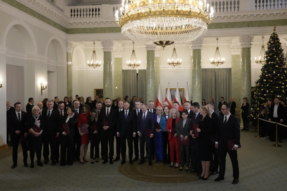 Poland's new Prime Minister Donald Tusk and Poland's President Andrzej Duda, centre, pose with cabinet members after the swearing-in ceremony at the presidential palace in Warsaw, Poland, Wednesday, Dec. 13, 2023. Donald Tusk was sworn in by the president in a ceremony where each of his ministers was also taking the oath of office. (AP Photo/Czarek Sokolowski)