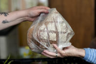 A volunteer gives a bag with bread to a woman at a food distribution center at the Catholic St. William Church in Berlin, Germany, Wednesday, May 31, 2023. German inflation eased to 6.1 % in May following several months of declines, even as Europe’s biggest economy registered another painful increase in food prices of nearly 15%. The Federal Statistical Office said Thursday that preliminary figures show that the annual inflation rate was lower than the 7.2% registered in April. (AP Photo/Markus Schreiber)