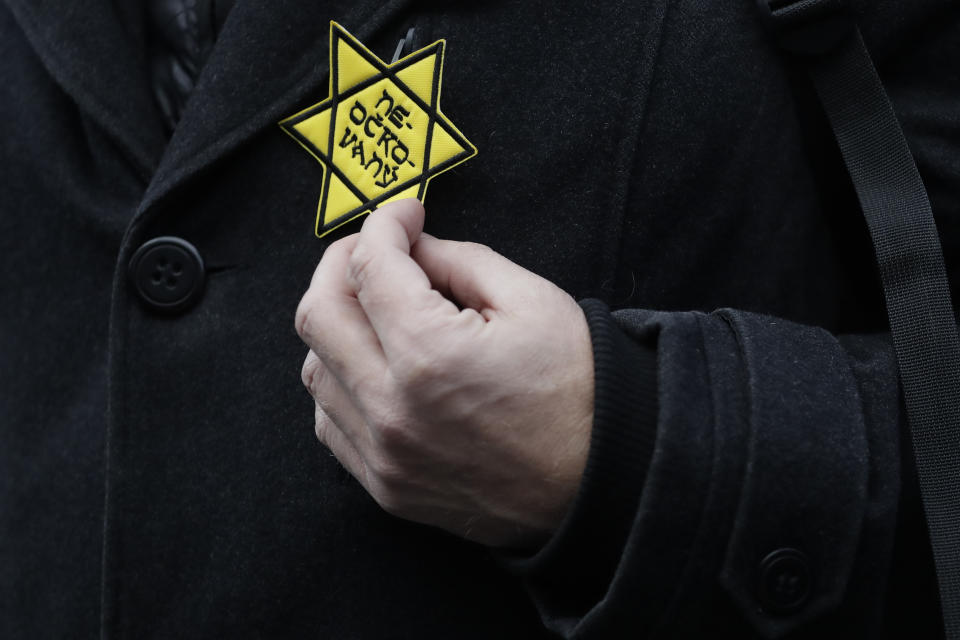 In this photo taken Friday, Jan. 8, 2021, a protesters holds a cloth badge in the shape of the Jewish Star of David reading: "unvaccinated" during a protest against the government's restrictive measures imposed to contain the coronavirus pandemic in Prague, Czech Republic. Across the Balkans and the rest of the nations in the southeastern corner of Europe, a vaccination campaign against the coronavirus is overshadowed by heated political debates or conspiracy theories that threaten to thwart the process. In countries like the Czech Republic, Serbia, Bosnia, Romania and Bulgaria, skeptics have ranged from former presidents to top athletes and doctors. Nations that once routinely went through mass inoculations under Communist leaders are deeply split over whether to take the vaccines at all. (AP Photo/Petr David Josek)