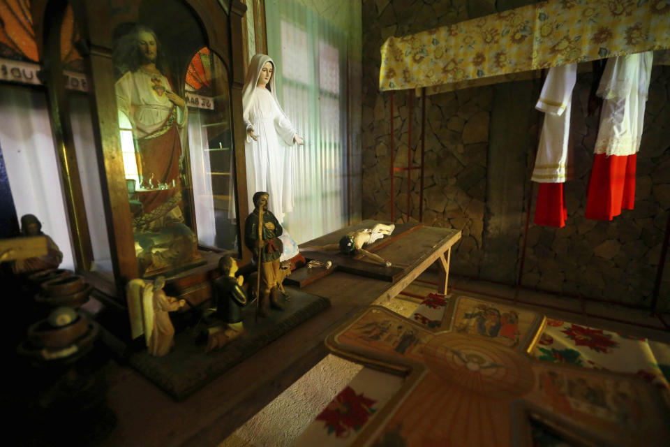 This Jan. 26, 2019 photo shows altar server vestments, right, and other religious images behind the altar chapel built by American priest Father Pius Hendricks in the village of Talustusan on Biliran Island in the central Philippines. Since December 2018, the small village has been rocked by controversy after about 20 boys and men accused the Catholic parish priest of years of alleged sexual abuse. (AP Photo/Bullit Marquez)