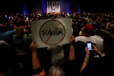 FILE PHOTO: A protester holds up a an anti-racism sign as Republican presidential nominee Donald Trump speaks during a campaign rally in Cedar Rapids, Iowa, U.S., July 28, 2016. REUTERS/Carlo Allegri/File Photo