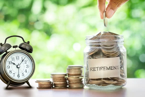 Retirement savings jar with coins and an alarm clock to the left.