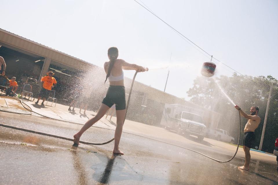 two people point water hoses at each other