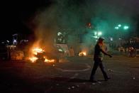 Manifestante camina cerca de un auto incendiado en San Cristóbal, capital del estado venezolano de Táchira el 22 de febrero de 2014 (AFP | Luis Robayo)