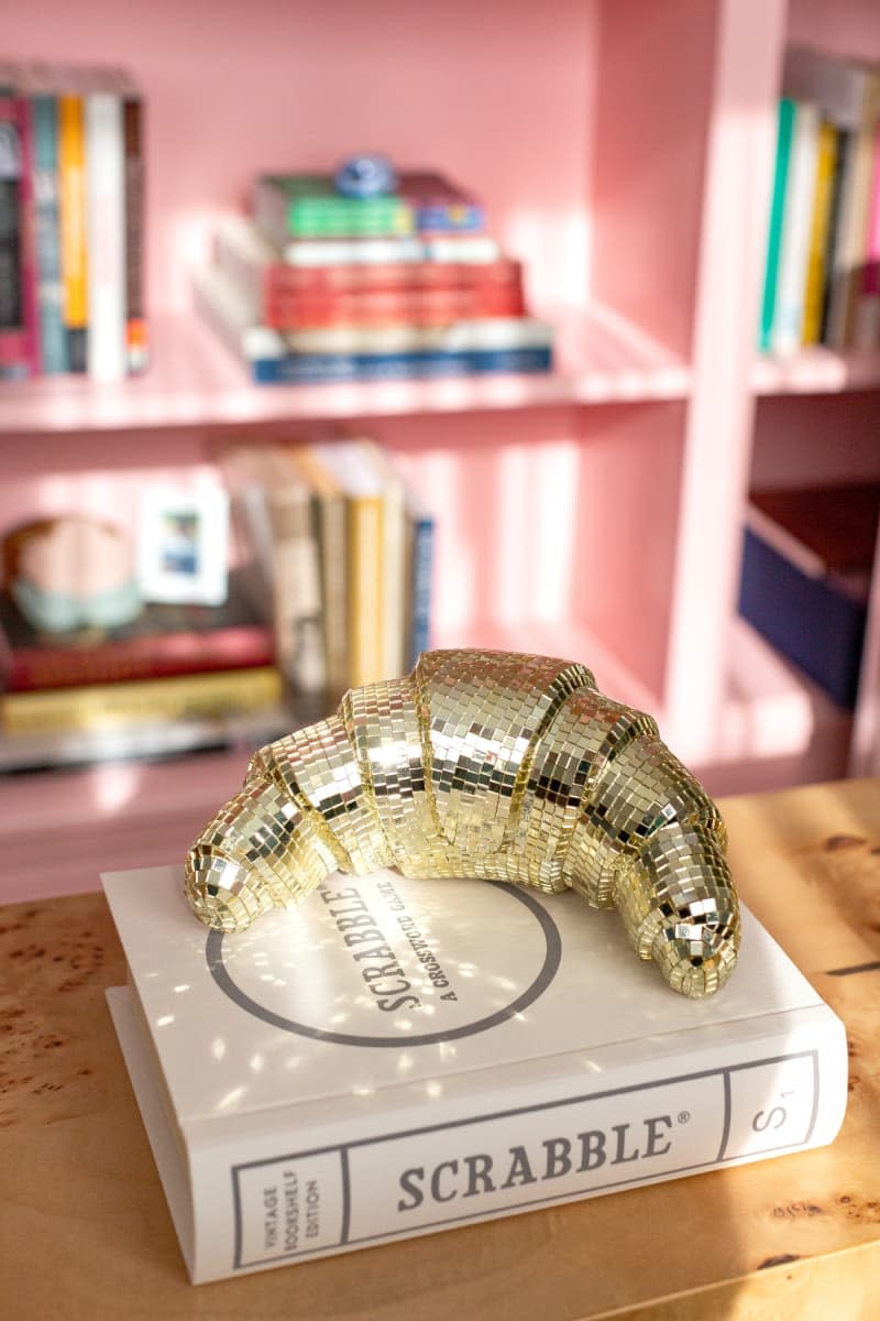 A mirrored golden croissant on a scrabble book.