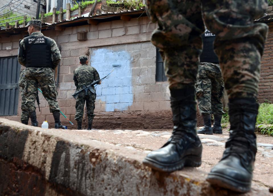 Honduras Military Police soldiers paint over gang graffiti on a wall in Tegucigalpa on Sept. 13, 2016. The U.S. Agency for International Development (USAID) has funded graffiti-removal programs throughout Central America, but President Donald Trump is now cutting foreign aid to the region.