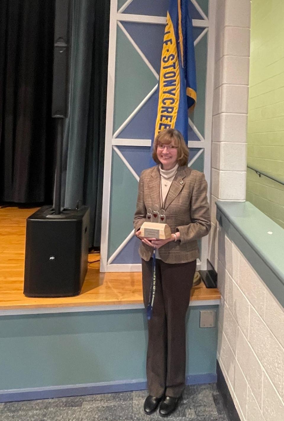 Rebecca Hutzell holding her 2023 Helper Award in the auditorium of the Shanksville Stonycreek Elementary School.