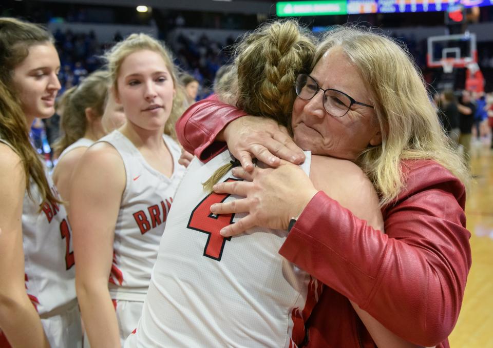 Brimfield head coach Maribeth Dura hugs senior forward Sophie Bedell (4) and the rest of the Brimfield Indians after their 32-31 win over Galena in the Class 1A state title game Saturday, March 5, 2022 at Redbird Arena in Normal.