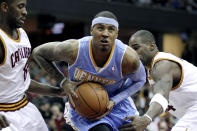 FILE - Denver Nuggets' Carmelo Anthony, center, drives to the hoop between Cleveland Cavaliers' Christian Eyenga, left, of the Congo, and Antawn Jamison in the first quarter of an NBA basketball game in Cleveland, Jan. 28, 2011. Now, with the Nuggets the top-seed in the Western Conference, Denver has never seemed to be mistaken for much beyond an NBA novelty. And if there really is gold at the end of all those rainbows, a real Nuggets fan will have to see it to believe it. (AP Photo/Amy Sancetta, File)
