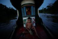 La mayoría de los hogares sobreviven de la pesca y la cosecha de frutas locales. En la imagen, Amadeu Amaral, de 7 años, navega con su padre a lo largo del río Parauau. (Foto: Uesley Marcelino / Reuters).