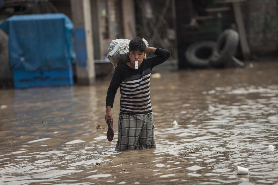 A man wades through a flooded street in Lima, Peru, Thursday, March 16, 2017. A new round of unusually heavy rains has killed at least a dozen people in Peru and now threatens flooding in the capital. Authorities said Thursday they expect the intense rains caused by the warming of surface waters in the eastern Pacific Ocean to continue another two weeks. (AP Photo/Rodrigo Abd)