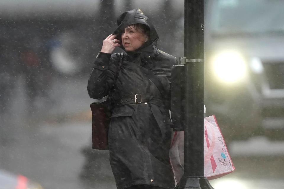 A passer-by grasps a pole while buffeted by wind and rain on a sidewalk, Monday, Dec. 18, 2023, in Boston. A storm moving up the East Coast brought heavy rain and high winds to the Northeast on Monday, threatening flooding, knocking out power to hundreds of thousands. (AP Photo/Steven Senne)