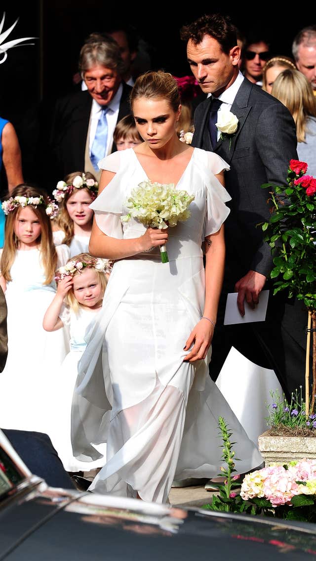 Cara Delevingne in a white dress with flowers at the wedding of her sister Poppy Delevingne and James Cook