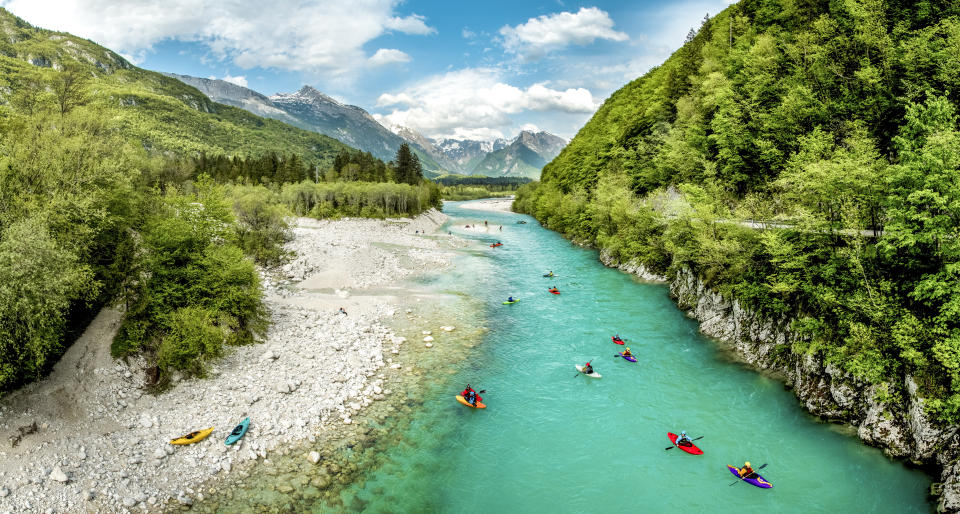 Group of people kayaking on the river Soča in Slovenia Europe. Scenic nature, with turquoise water river, surrounded with bushy forest in the summer time.