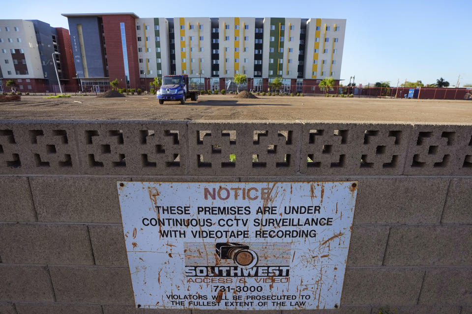 The back wall of the Periwinkle Mobile Home Park separates a recently cleared lot being prepared for construction and student housing, Thursday, April 11, 2023, in Phoenix. Residents of the park are facing an eviction deadline of May 28 due to a private university's plan to redevelop the land for student housing. (AP Photo/Matt York)