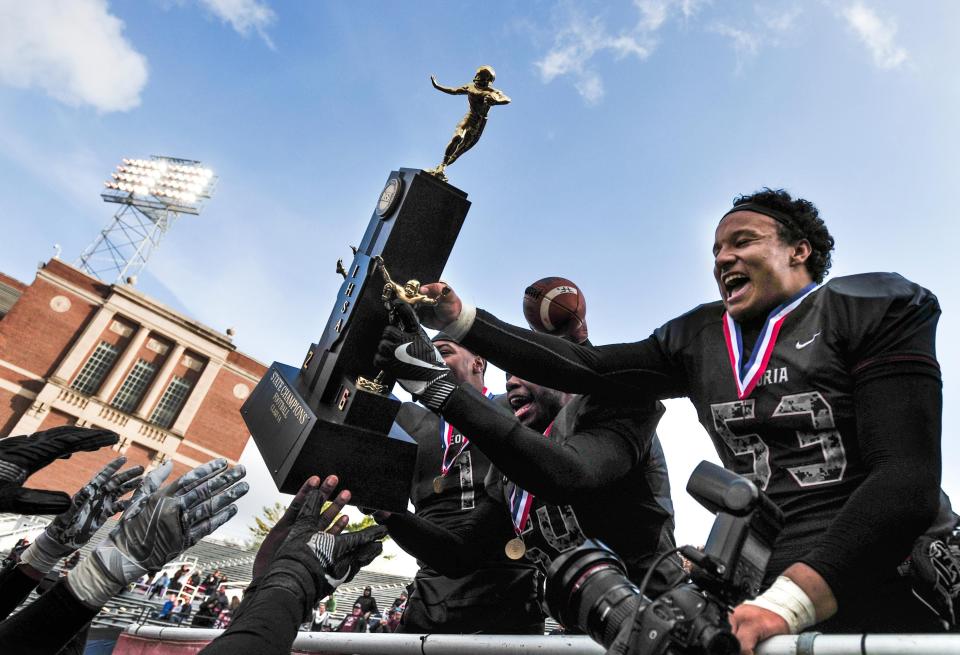 Peoria High graduate Kendrick Green and teammates pass around the championship trophy after the 2016 Class 5A title game at Memorial Stadium in Champaign.