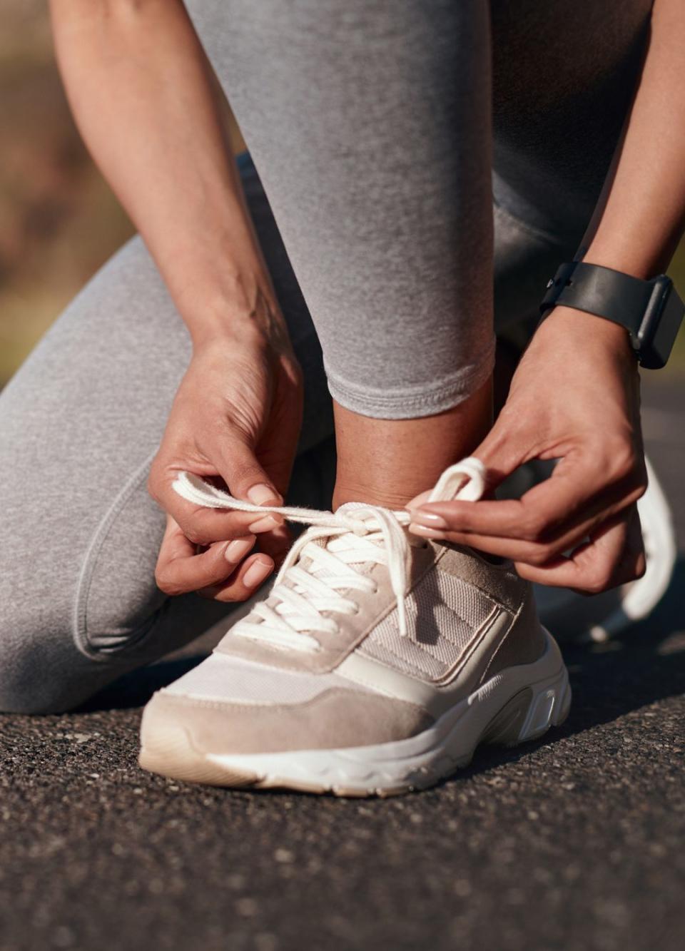 Fitness, road and woman tie her sneakers before training for a running marathon, race or competition