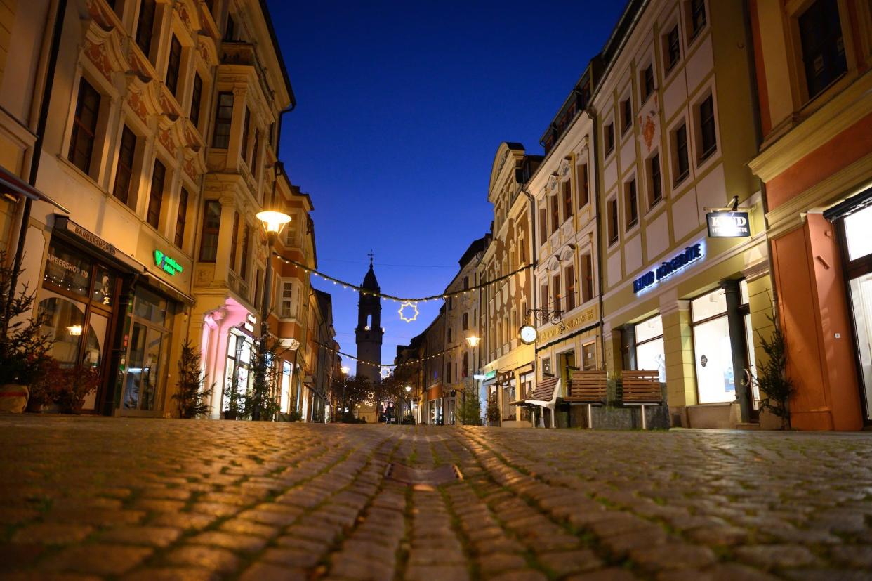 18 December 2020, Saxony, Bautzen: Christmas lights hang over the empty Reichenstraße in front of the Reichenturm. So far, there has been no sign of a turnaround in new infections in the state of Saxony. According to the Ministry of Health in Dresden, the seven-day incidence climbed to 415 on Thursday (17.12.2020). On Wednesday, the value was still at 407. Saxony thus continues to be well ahead of all other federal states. Photo: Sebastian Kahnert/dpa-Zentralbild/dpa (Photo by Sebastian Kahnert/picture alliance via Getty Images)