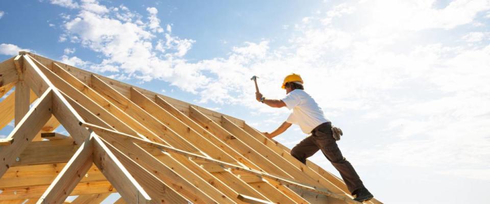 A roofer gets to work building a house.