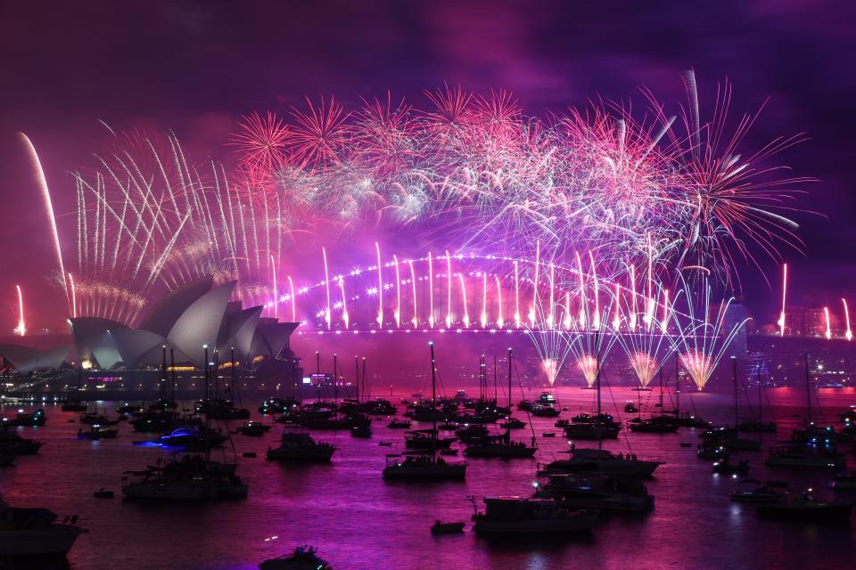 New Year's Eve fireworks light up the sky over the Sydney Opera House (L) and Harbour Bridge (AFP via Getty Images)