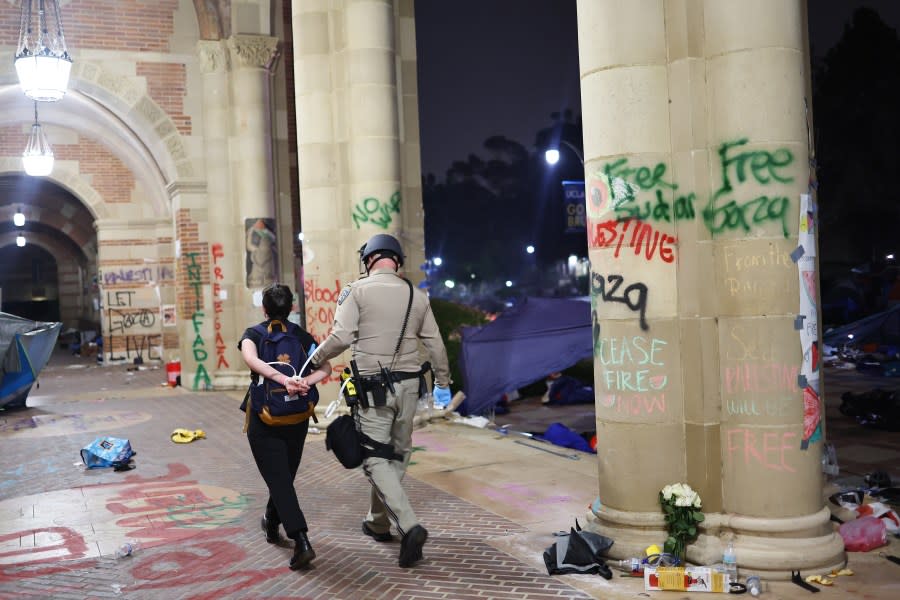 LOS ANGELES, CALIFORNIA – MAY 02: A California Highway Patrol (CHP) officer detains a protestor near encampment graffiti while clearing a pro-Palestinian encampment after dispersal orders were given at the University of California, Los Angeles (UCLA) campus, on May 2, 2024 in Los Angeles, California. The camp was declared ‘unlawful’ by the university and over 100 protestors who refused to leave were detained during the operation. Pro-Palestinian encampments have sprung up at college campuses around the country with some protestors calling for schools to divest from Israeli interests amid the ongoing war in Gaza. (Photo by Mario Tama/Getty Images)