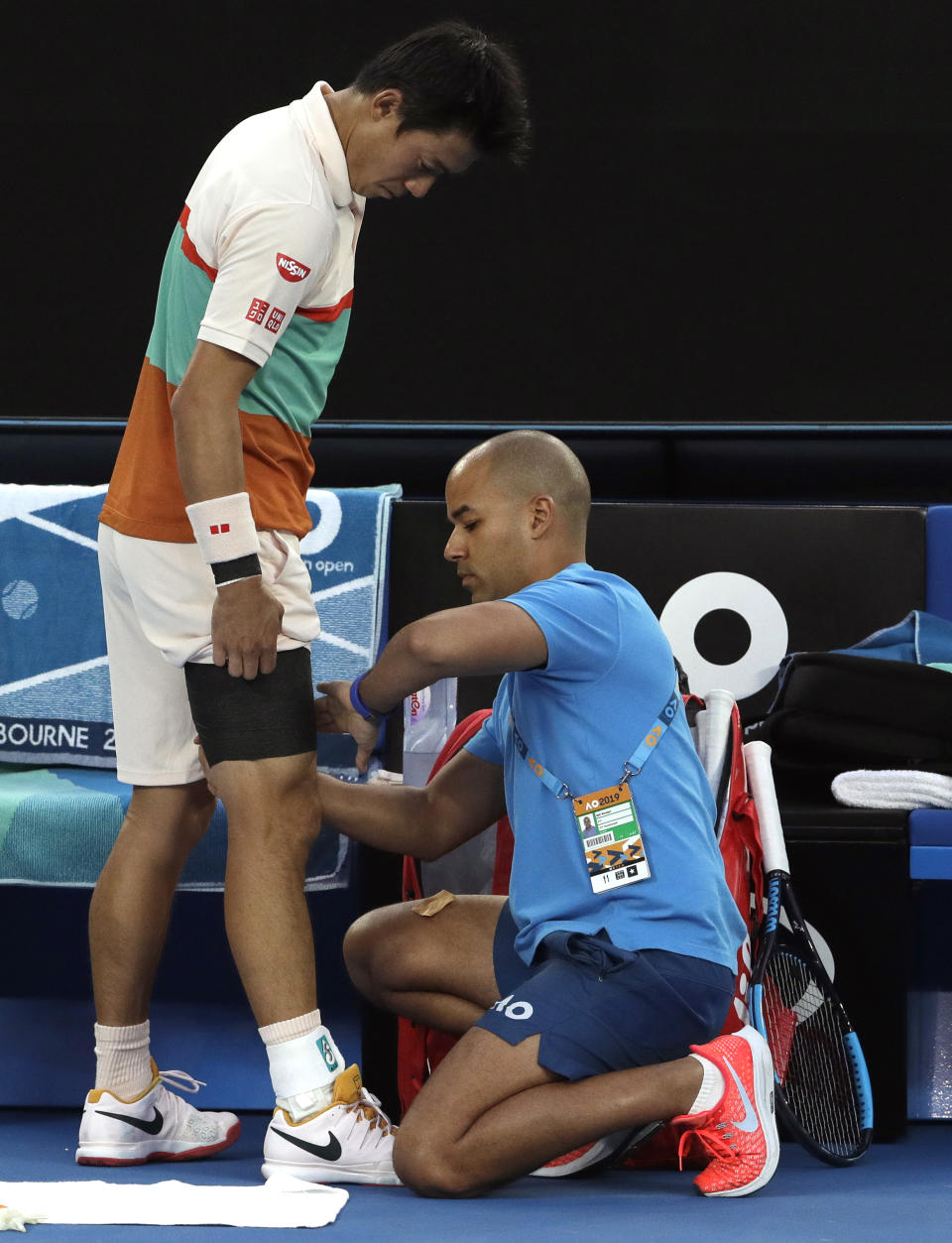 Japan's Kei Nishikori has his leg strapped by a trainer during his quarterfinal match against Serbia's Novak Djokovic at the Australian Open tennis championships in Melbourne, Australia, Wednesday, Jan. 23, 2019. (AP Photo/Mark Schiefelbein)