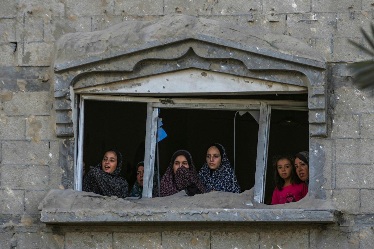 Palestinians look at the destruction after an Israeli airstrike on a crowded tent camp housing Palestinians displaced by the war in Muwasi, Gaza Strip