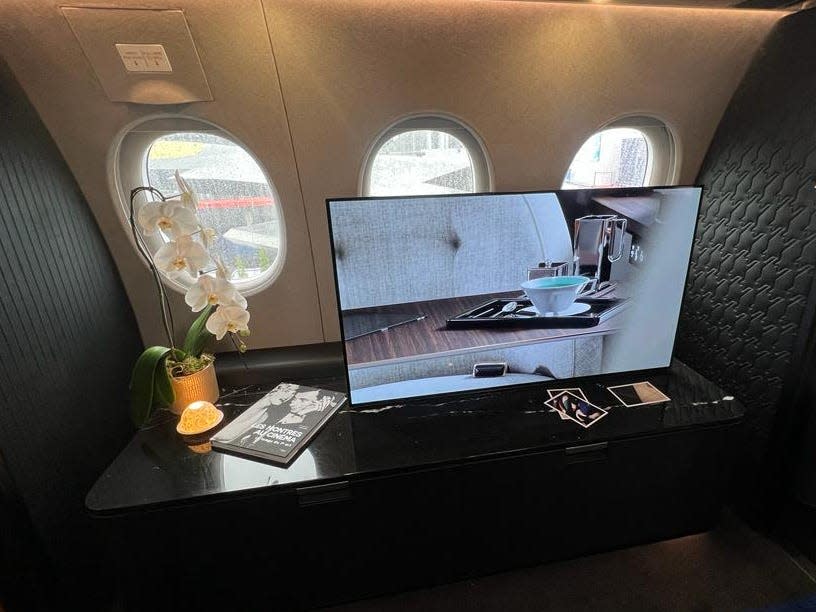 A television atop a black counter with a book and flowers, with three windows behind, on a Falcon 10X