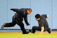 A fan who ran onto the field slips and falls as he is tackled by a security guard during the ninth inning of the basbeall game between Los Angeles Dodgers and Pittsburgh Pirates on April 29, 2010 at Dodger Stadium in Los Angeles, California. (Photo by Kevork Djansezian/Getty Images)