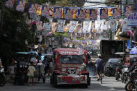 A passenger jeepney passes campaign posters outside a polling center in Manila, Philippines on May 6, 2022. The winner of May 9, Monday's vote will inherit a sagging economy, poverty and deep divisions, as well as calls to prosecute outgoing leader Rodrigo Duterte for thousands of deaths as part of a crackdown on illegal drugs. (AP Photo/Aaron Favila)