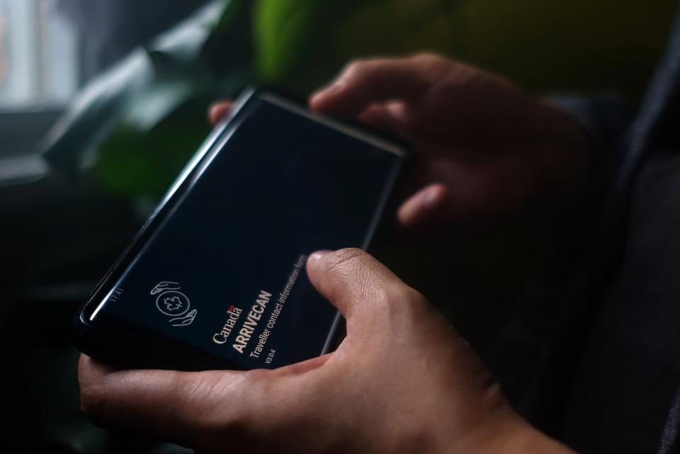 A person holds a smartphone set to the opening screen of the ArriveCan app.