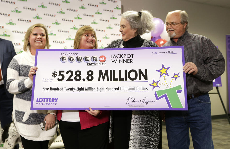 Rebecca Hargrove, second from right, president and CEO of the Tennessee Lottery, presents a ceremonial check to John Robinson, right; his wife, Lisa, second from left; and their daughter, Tiffany, left; after the Robinsons’ winning Powerball ticket was authenticated at the Tennessee Lottery headquarters on Friday in Nashville, Tenn. The ticket was one of three winning tickets in the $1.6 billion jackpot drawing. (AP Photo/Mark Humphrey)