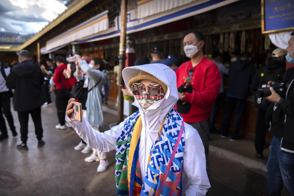 A tourist takes a smartphone photo at the Jokhang Temple in Lhasa in western China's Tibet Autonomous Region, Tuesday, June 1, 2021. Tourism is booming in Tibet as more Chinese travel in-country because of the coronavirus pandemic, posing risks to the region's fragile environment and historic sites. (AP Photo/Mark Schiefelbein)