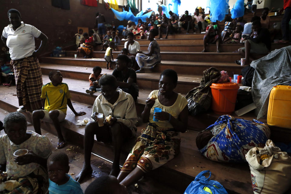 Displaced families, victims of Cyclone Idai, eat lunch at the Samora Machel Secondary School which is being used to house victims of the floods in Beira, Mozambique, Sunday March 24, 2019. The death toll has risen above 750 in the three southern African countries hit 10 days ago by the cyclone storm, as workers restore electricity, water and try to prevent outbreak of cholera, authorities said Sunday. (AP Photo/Phill Magakoe)