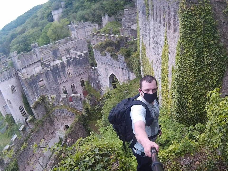 John Walker in the castle's ruins holding a selfie stick