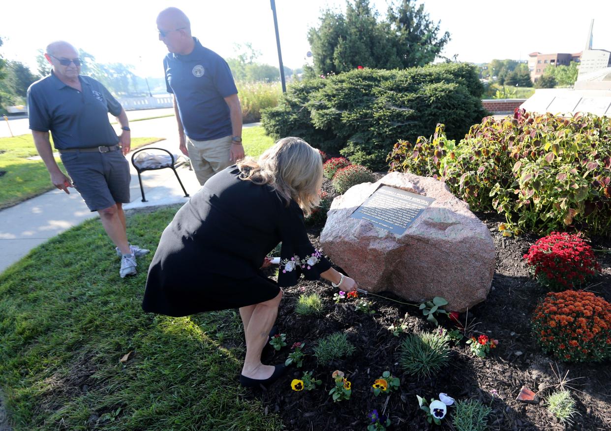 Kathy Andresen, whose husband died in 2020 in a workplace accident, places a rose at the base of the Mishawaka Workers Memorial Monday, Sept. 4, 2023, at the dedication ceremony of the new stone and plaque at the Ball Band Monument site at Main Street and Mishawaka Avenue.